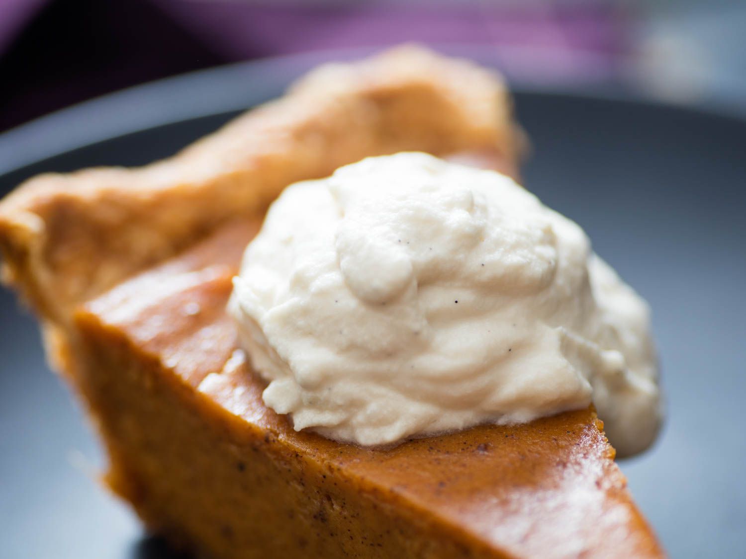 Closeup of brown sugar whipped cream dolloped on a slice of sweet potato pie.