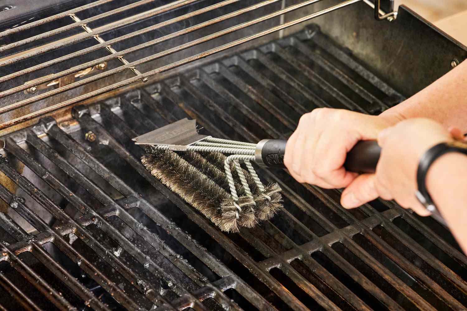 A person cleans the grill on the Weber Spirit EX-325s Smart Grill
