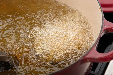 A pot of oil is bubbling while food is being fried