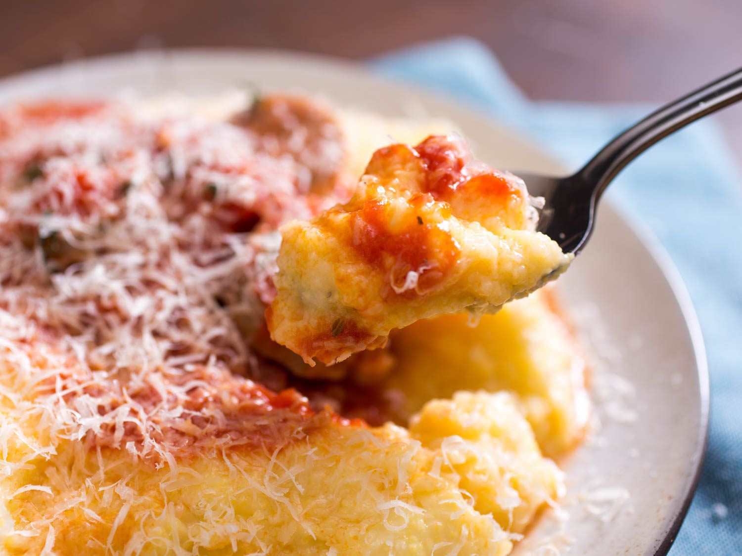 Polenta being scooped out of a plate using a spoon.