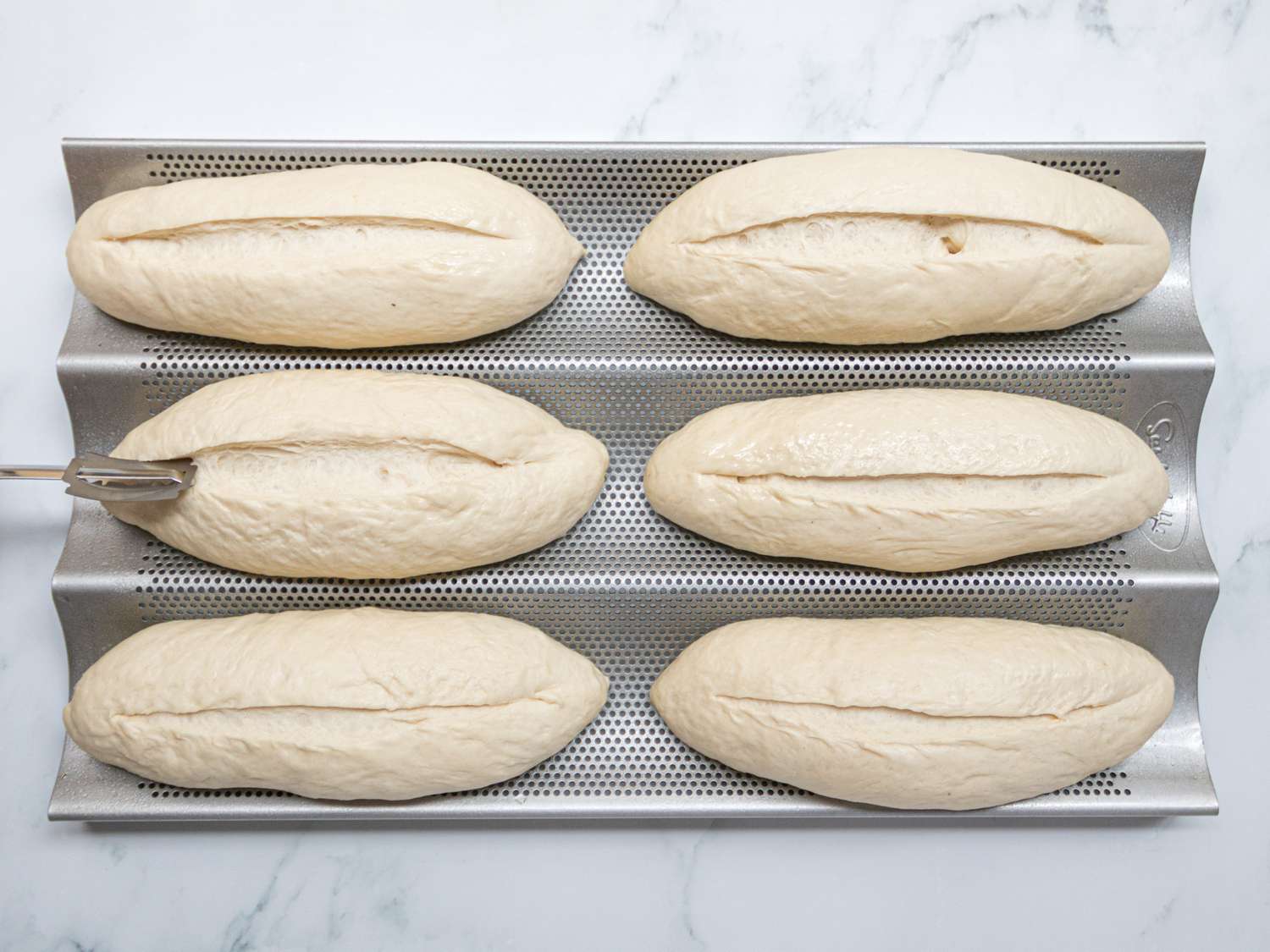 Overhead view of slicing banh mi loaves down the center line