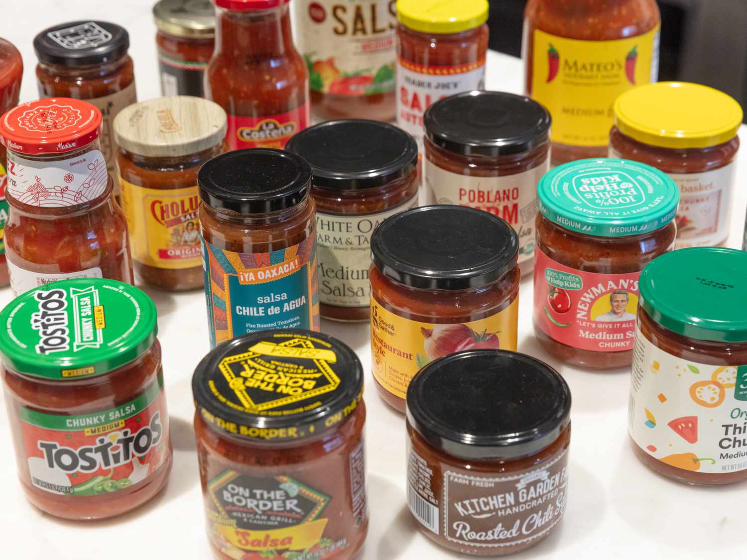 An assortment of jars of salsa arranged on a table, featuring various brands and flavors
