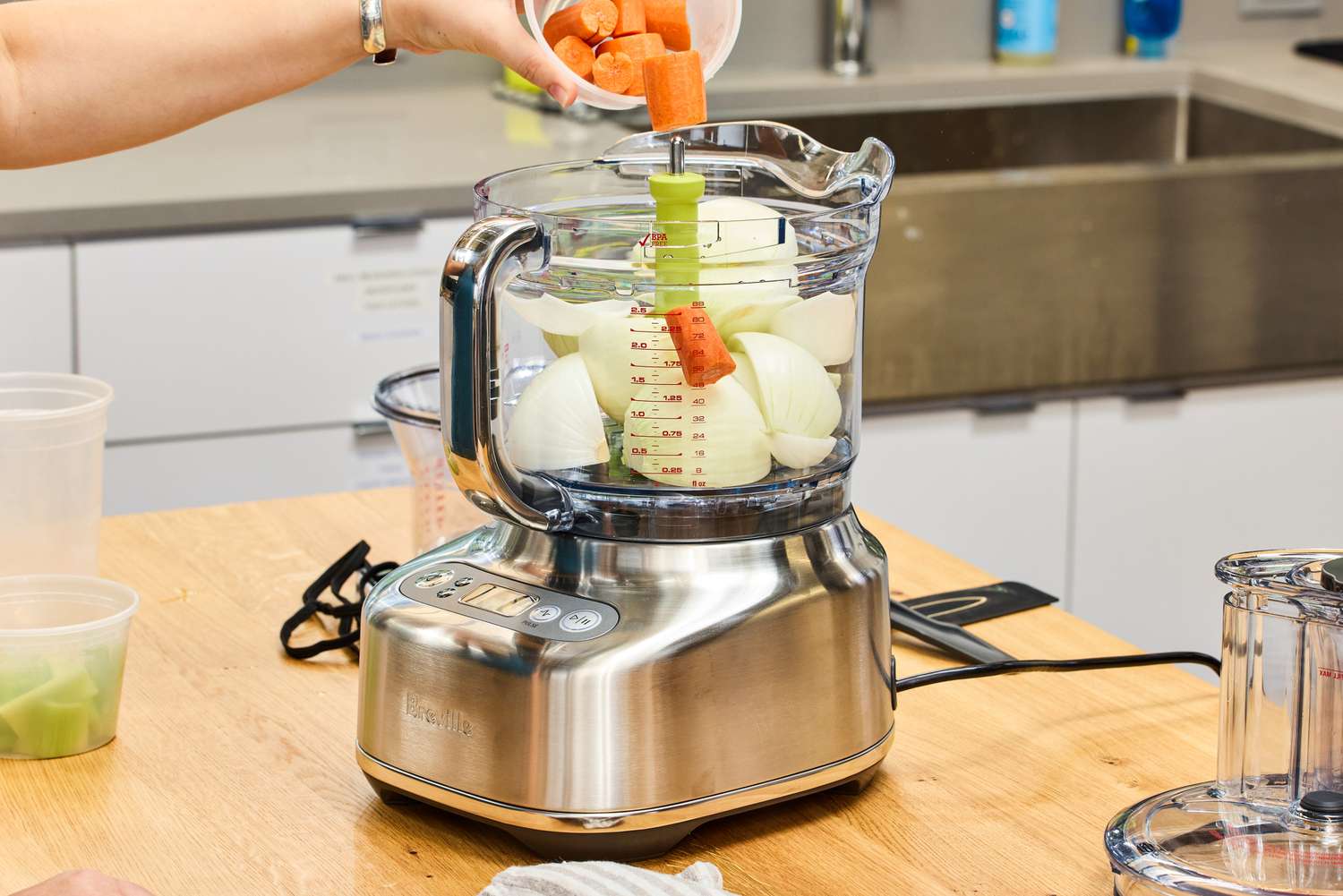 A person puts vegetables into the Breville BFP838BSS1BNA1 16-Cup Paradice Food Processor