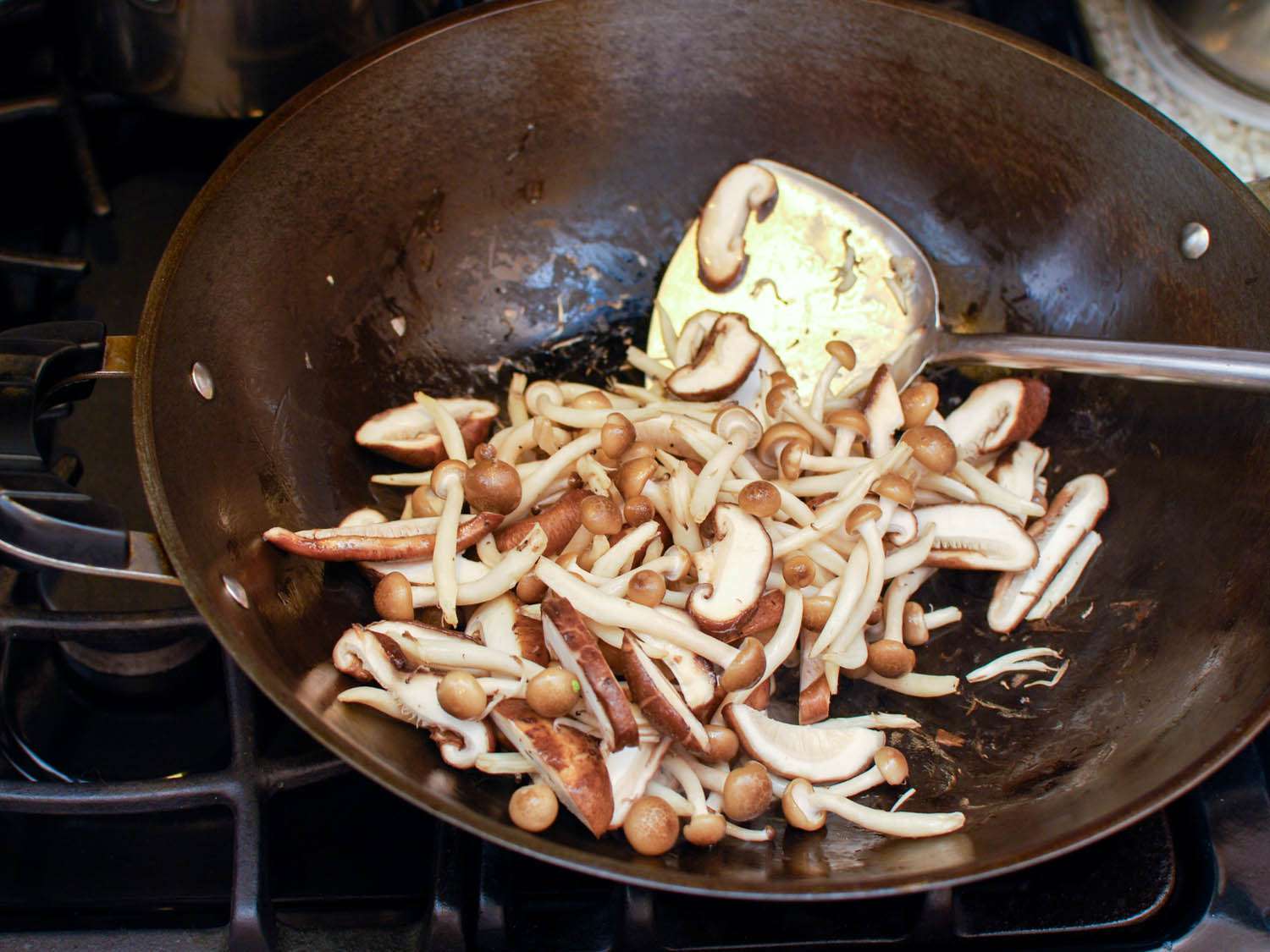 Fresh sliced mushrooms are stir-fried in the wok.