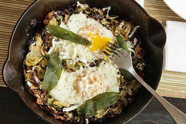Brussels Sprouts Hash With Fried Sage and Soft Cooked Eggs in a cast iron skillet.