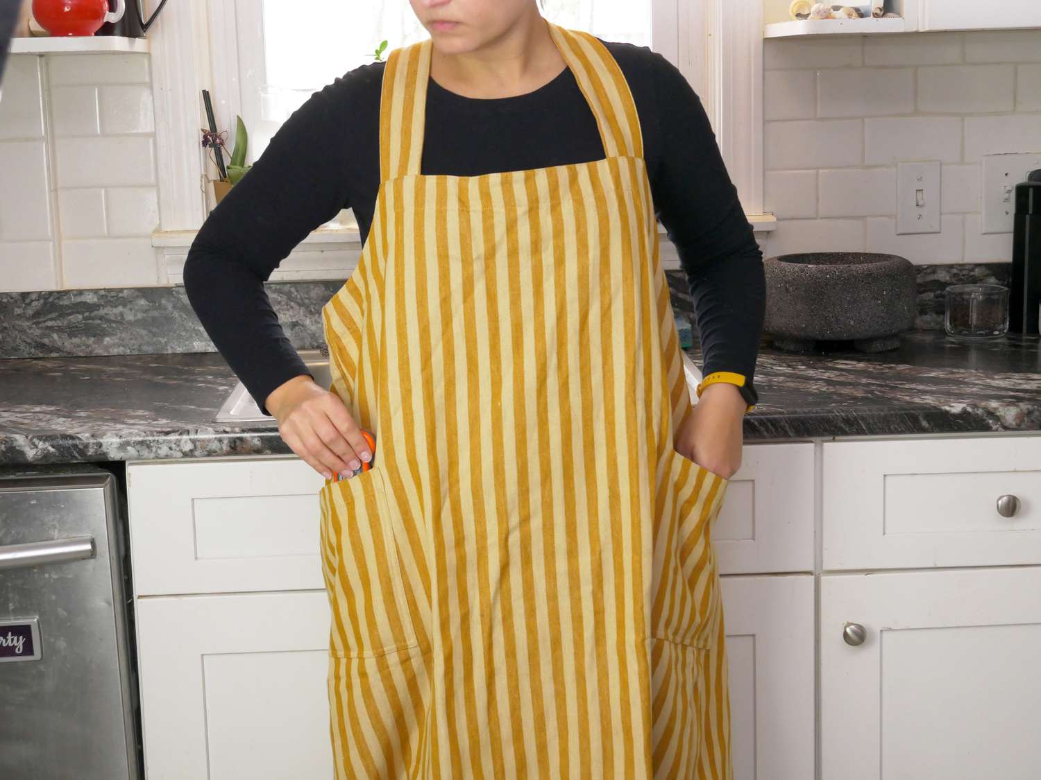 a person pulling a thermometer out of the pocket on the minna apron