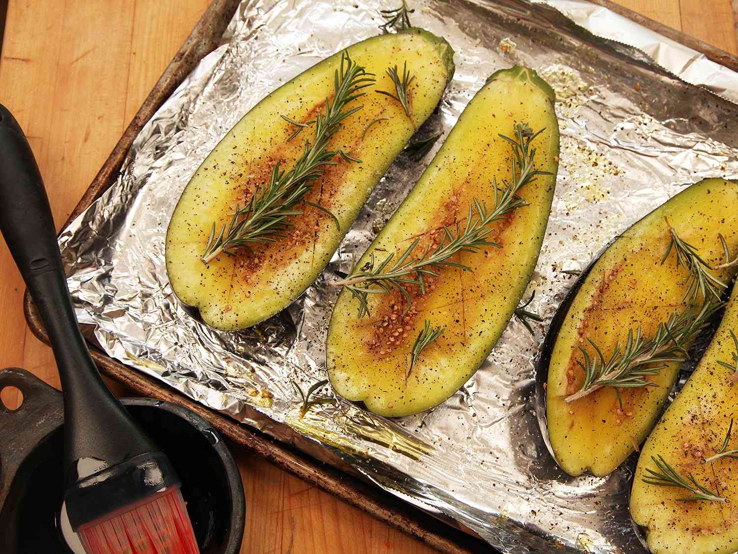 The brushed eggplant halves are topped with sprigs of rosemary.
