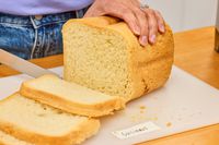 A person using a cutting board to slice bread made in the Cuisinart CBK-110 Compact Automatic Bread Maker