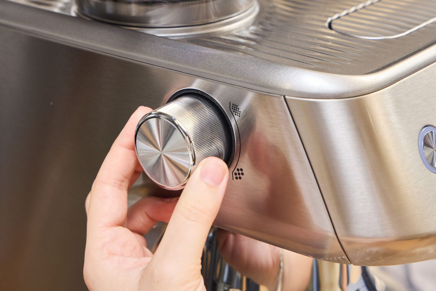 A person turns a dial on the side of the Breville The Oracle Jet Espresso Machine
