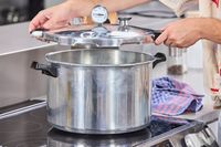 A person lifting the lid from the Presto 16-Quart Pressure Canner and Cooker