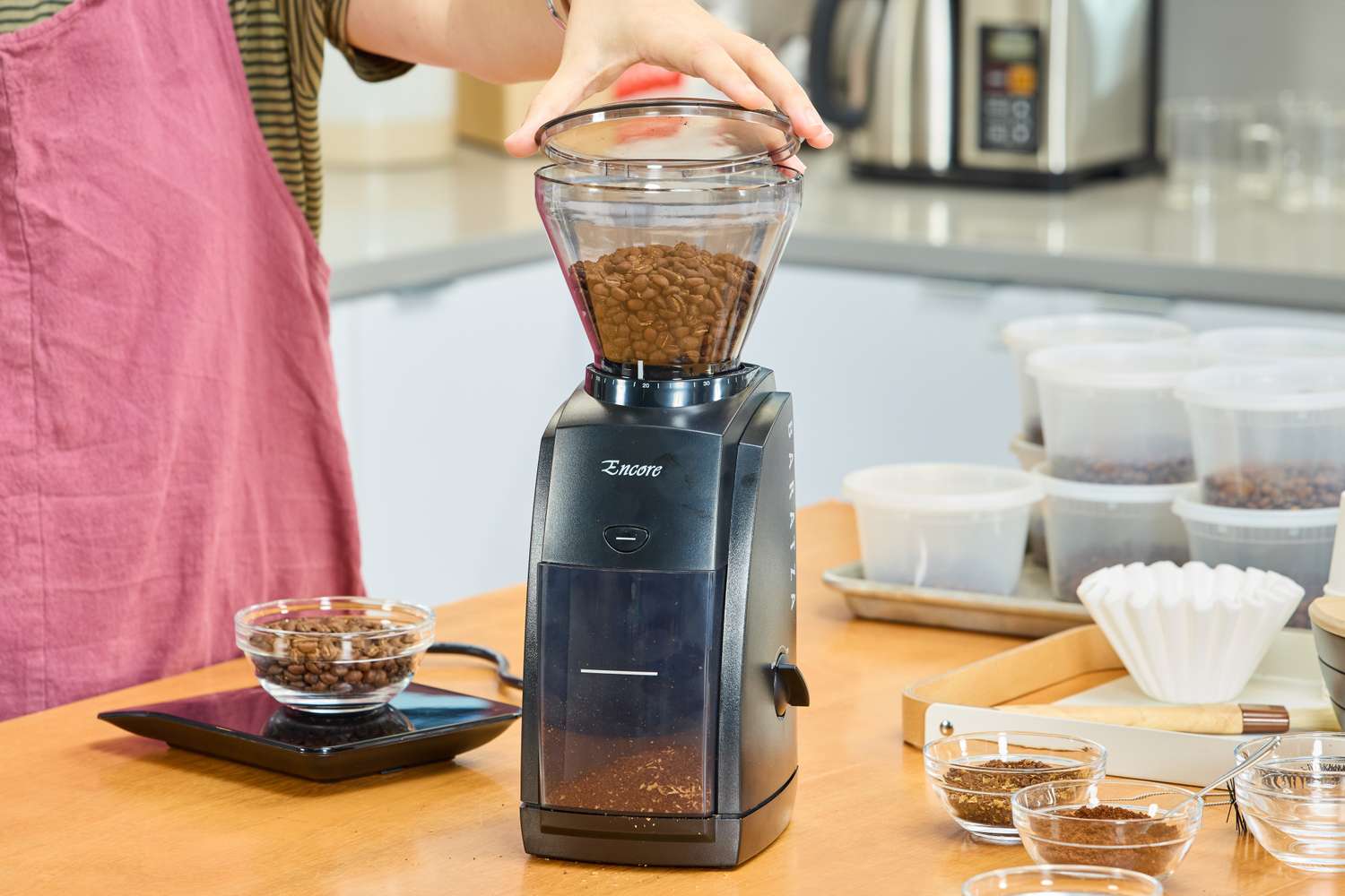 A person uses the Baratza Encore Conical Burr Coffee Grinder to grind coffee beans