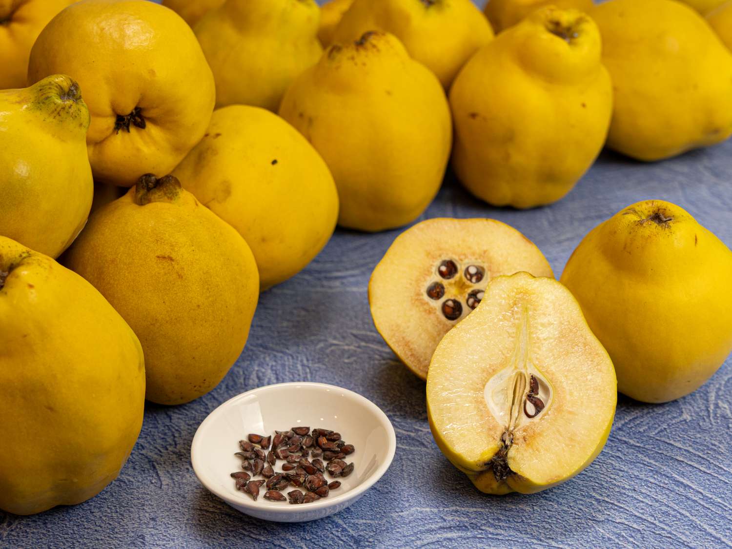 A group of quince fruits and a sliced quince revealing seeds