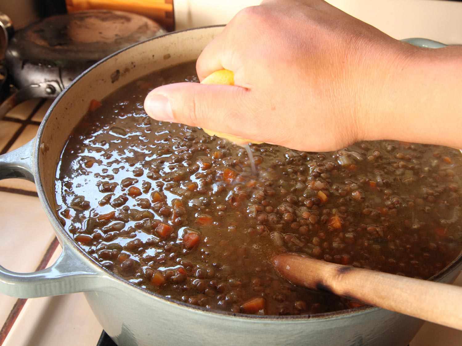 Squeezing lemon juice into finished lentil soup.