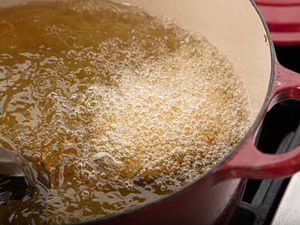 A pot of oil is bubbling while food is being fried