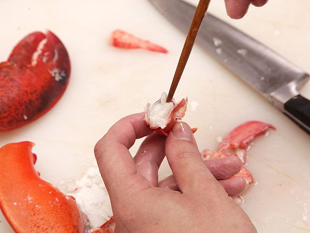 Fishing meat out from the small pincer of a lobster claw using a chopstick