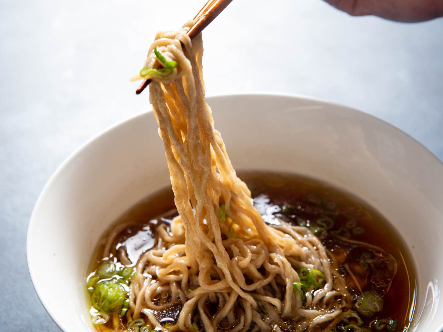 Chopsticks pulling temomi noodles out of a bowl of ramen