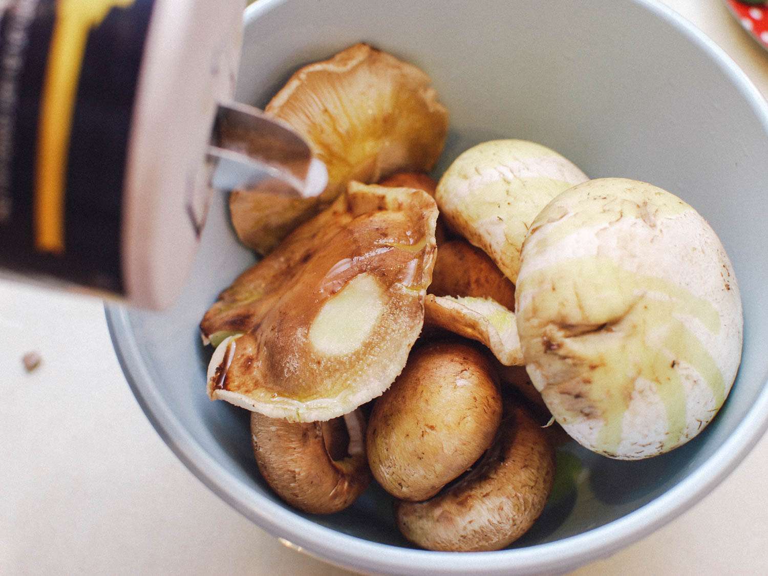 Seasoning a bowl of mushrooms with salt.