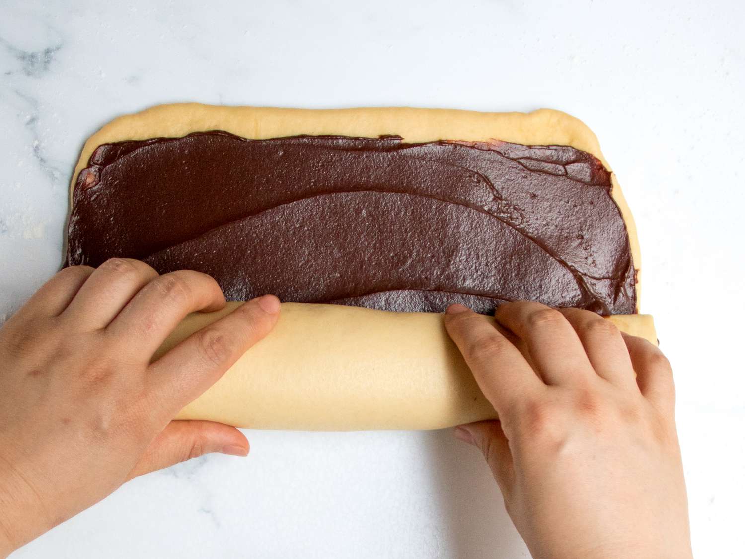 Hands rolling the dough tightly