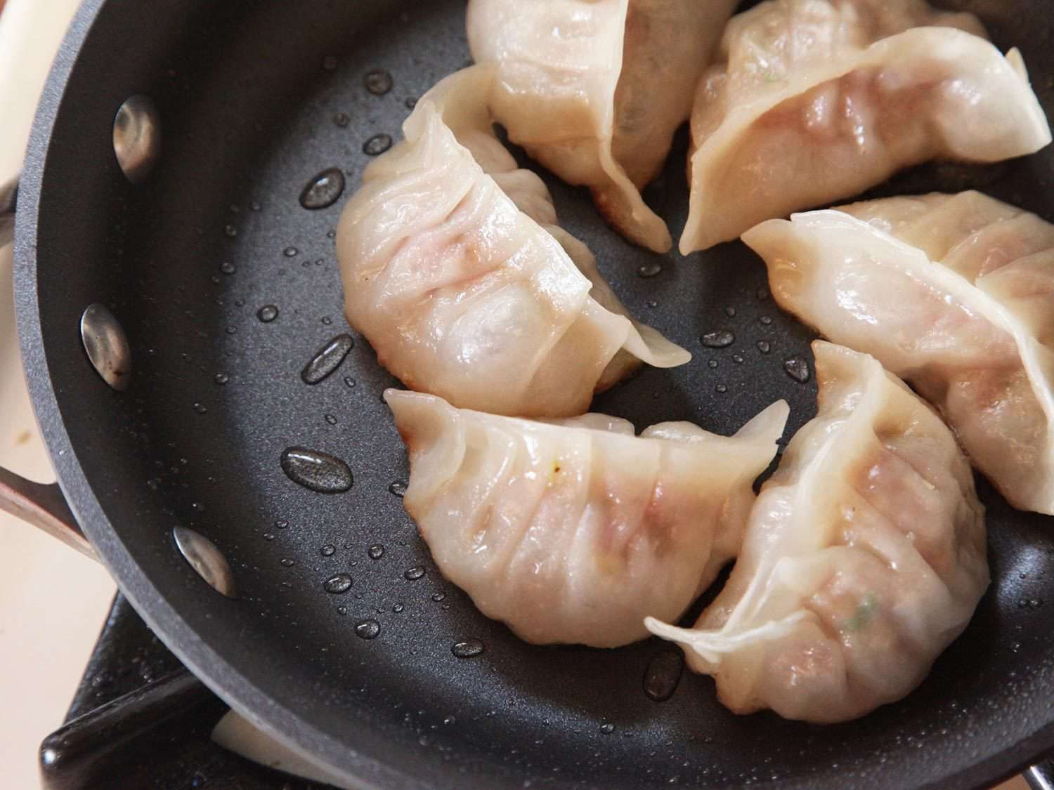 Water cooks off in a pan of dumplings.
