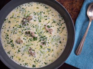 Overhead closeup of a bowl of oyster stew, garnished with fennel fronds and minced chive. 