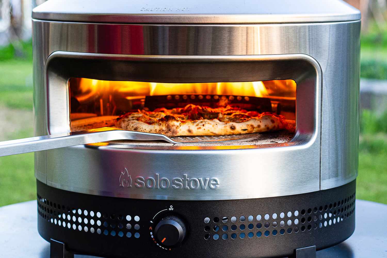 Pizza being cooked in a Solo Stove Pi Prime pizza oven with flames inside