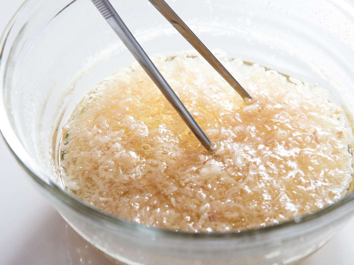 Stirring a microwaved bowl of shallots frying in oil.