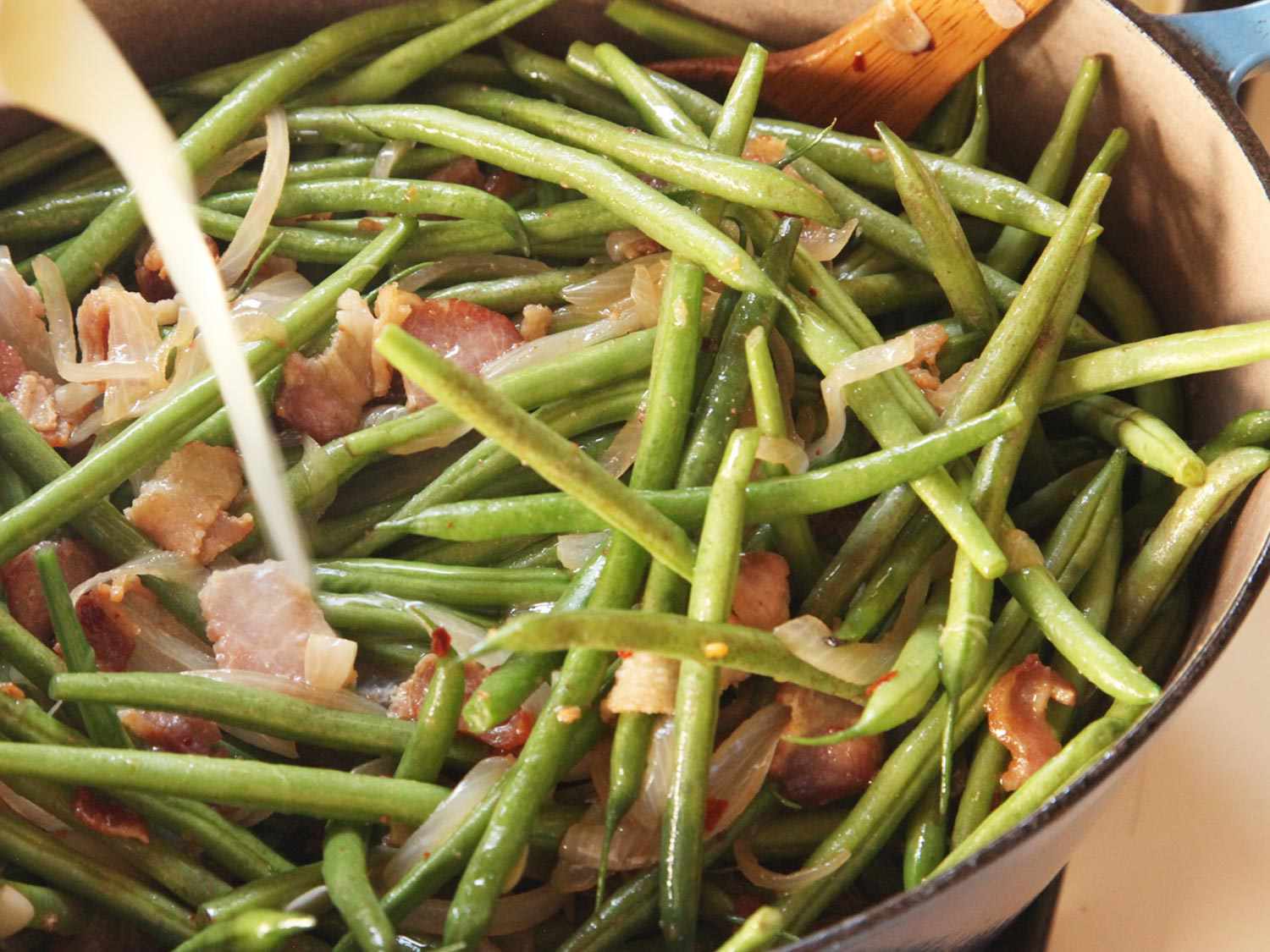 Adding stock to green beans, onions, and bacon in Dutch oven