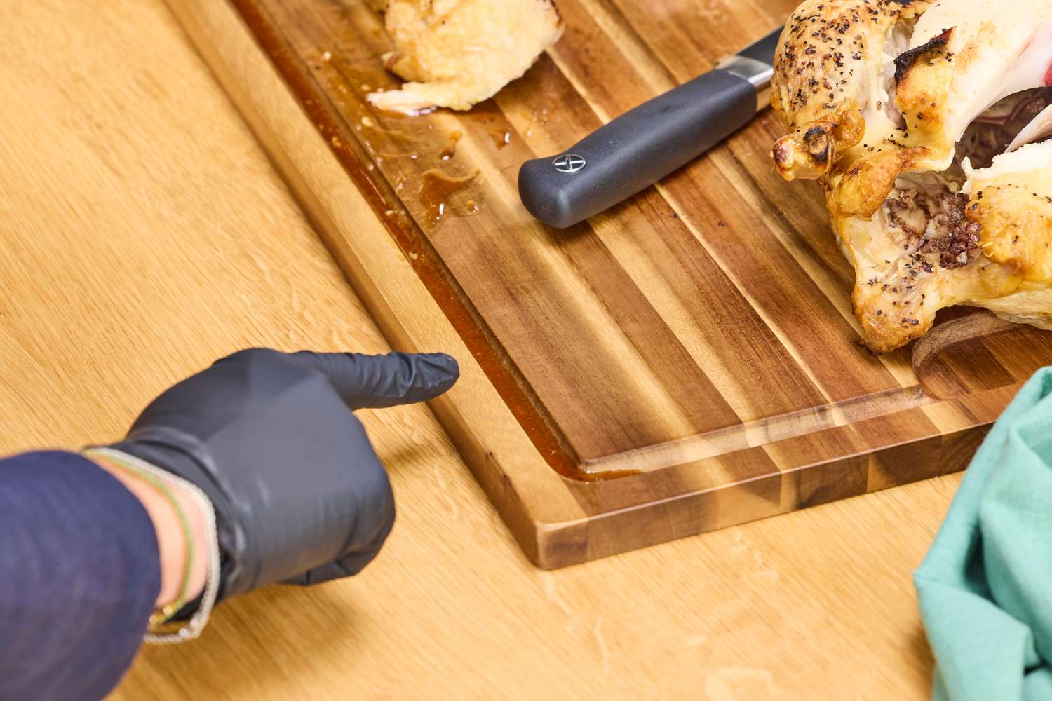 A person pointing to an almost-overflowing juice trench in a carving board