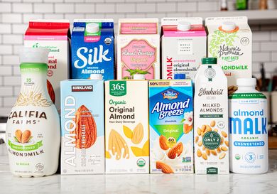 Various brands of almond milk cartons and bottles arranged on a countertop showcasing a variety of packaging designs and labels