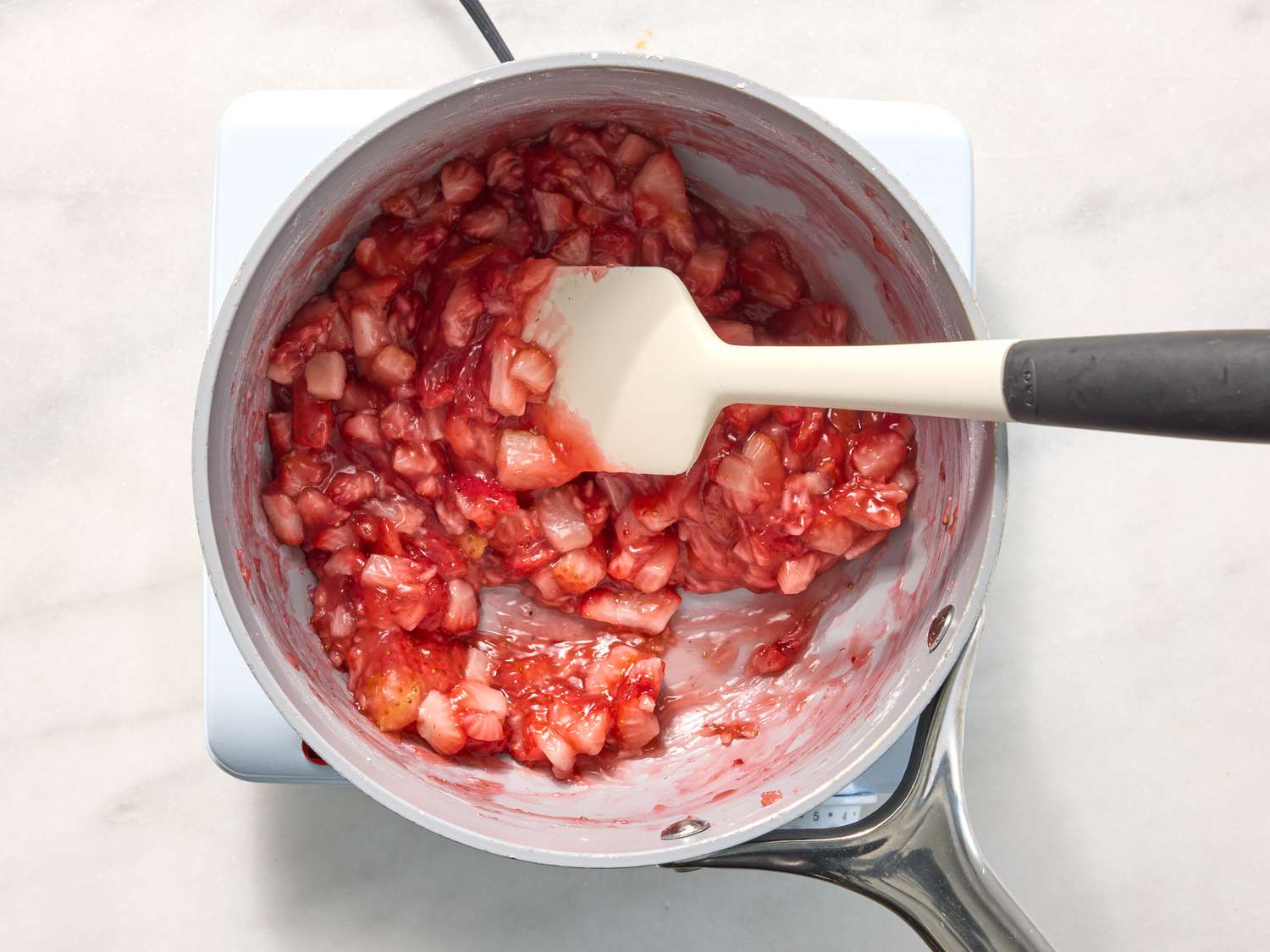 mixing strawberries together with sugar and cornstarch in saucepan 