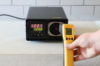 a person pointing an infrared thermometer at a calibration box