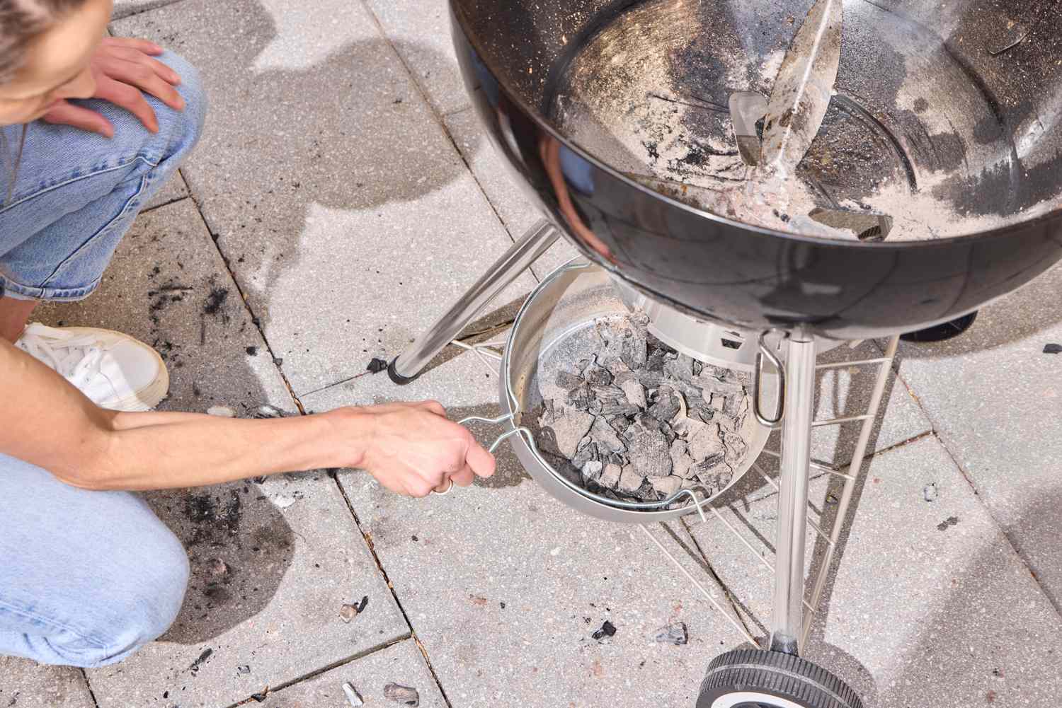 A person removing the bottom of the Weber Original Kettle Premium 22-Inch Charcoal Grill
