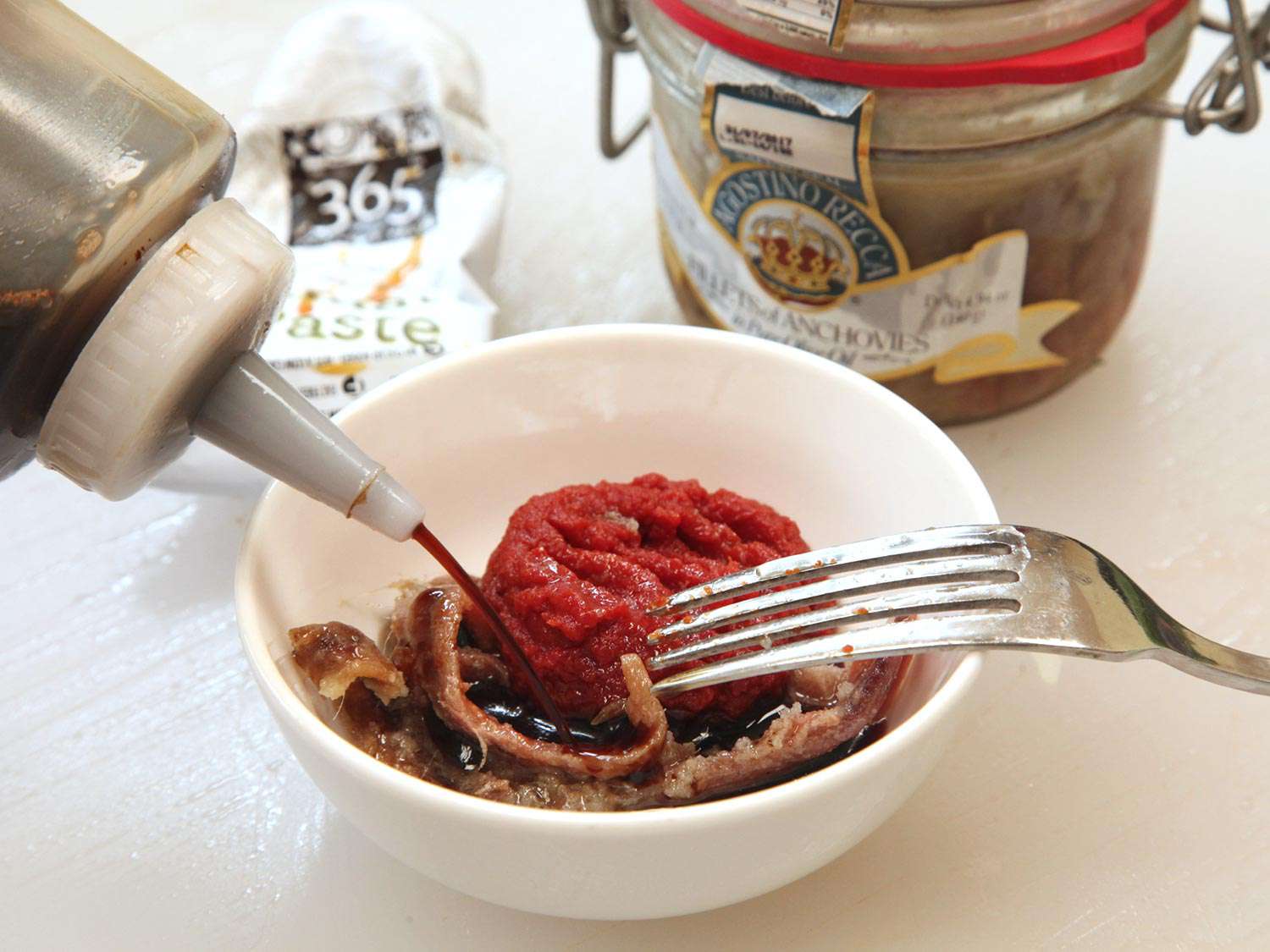 Small white bowl with anchovies, tomato paste, Worcestershire sauce, and soy sauce.