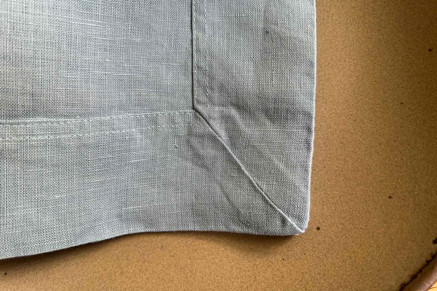 Close-up of a stitched corner of a piece of fabric on a flat surface