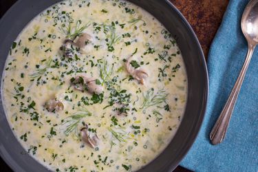Overhead closeup of a bowl of oyster stew, garnished with fennel fronds and minced chive. 