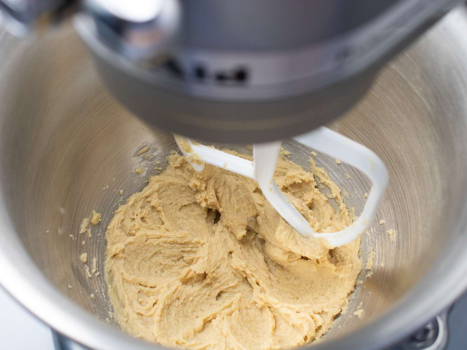 An overhead view of brown sugar and butter being mixed together in a stand mixer.