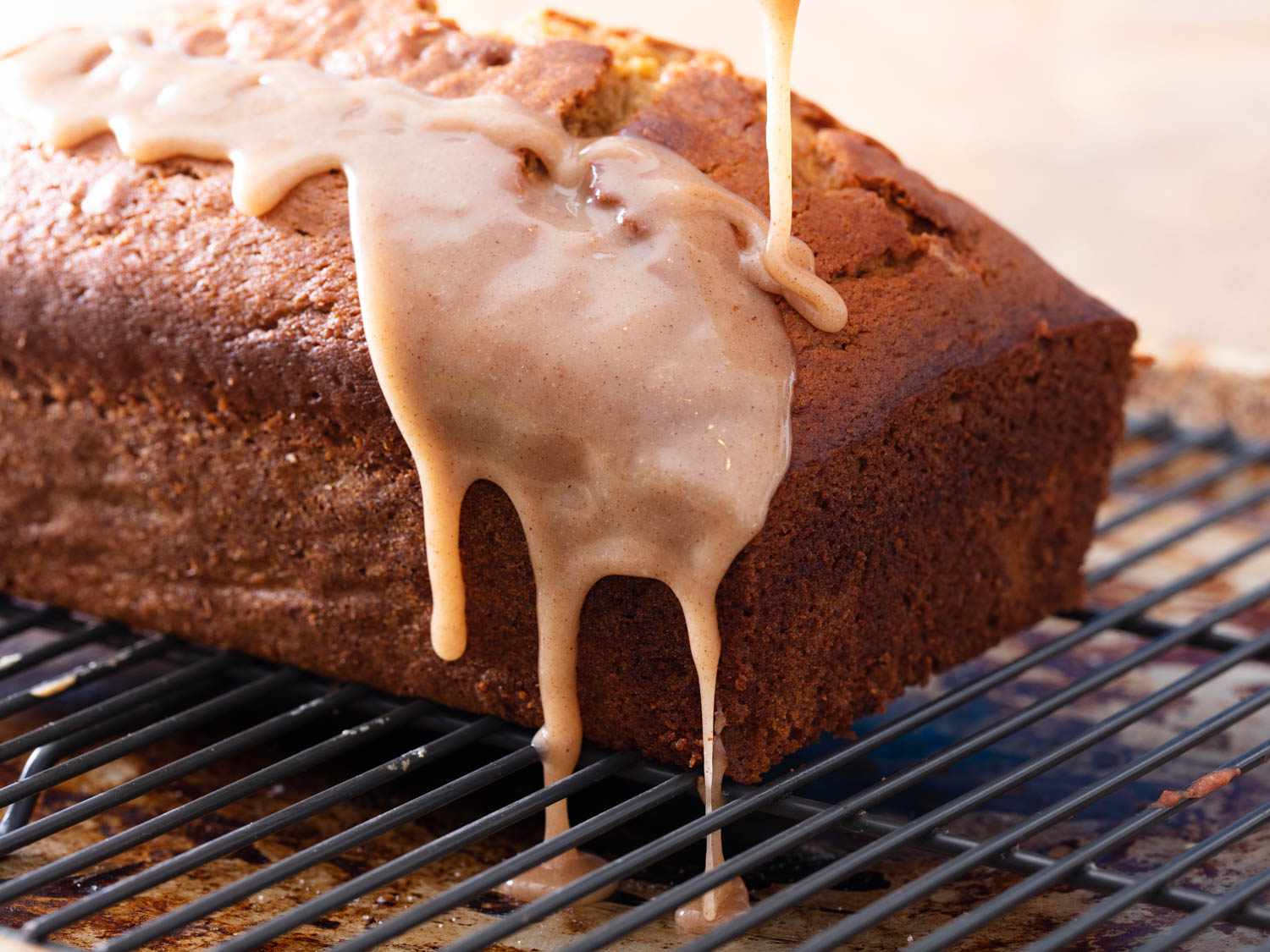 Drizzling glaze over pumpkin bread so it drips down the sides.