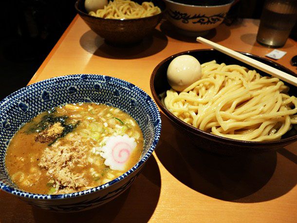 A bowl of Tsukemen with noodles in a bowl next to a bowl of broth. 