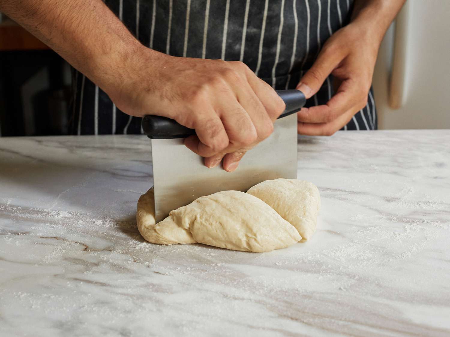 A person cutting pasta using the OXO Bench Scraper
