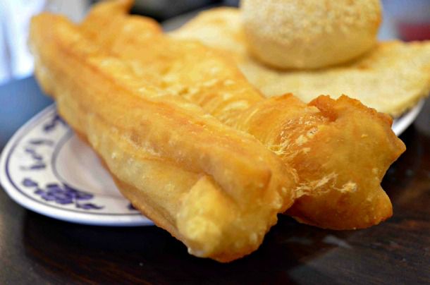 Closeup of a twisted cruller, or youtiao, served on a small plate.