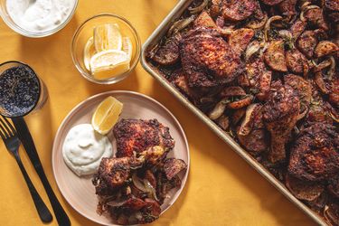 Sheet pan with roasted chicken and potatoes plate served with yogurt and lemon slices
