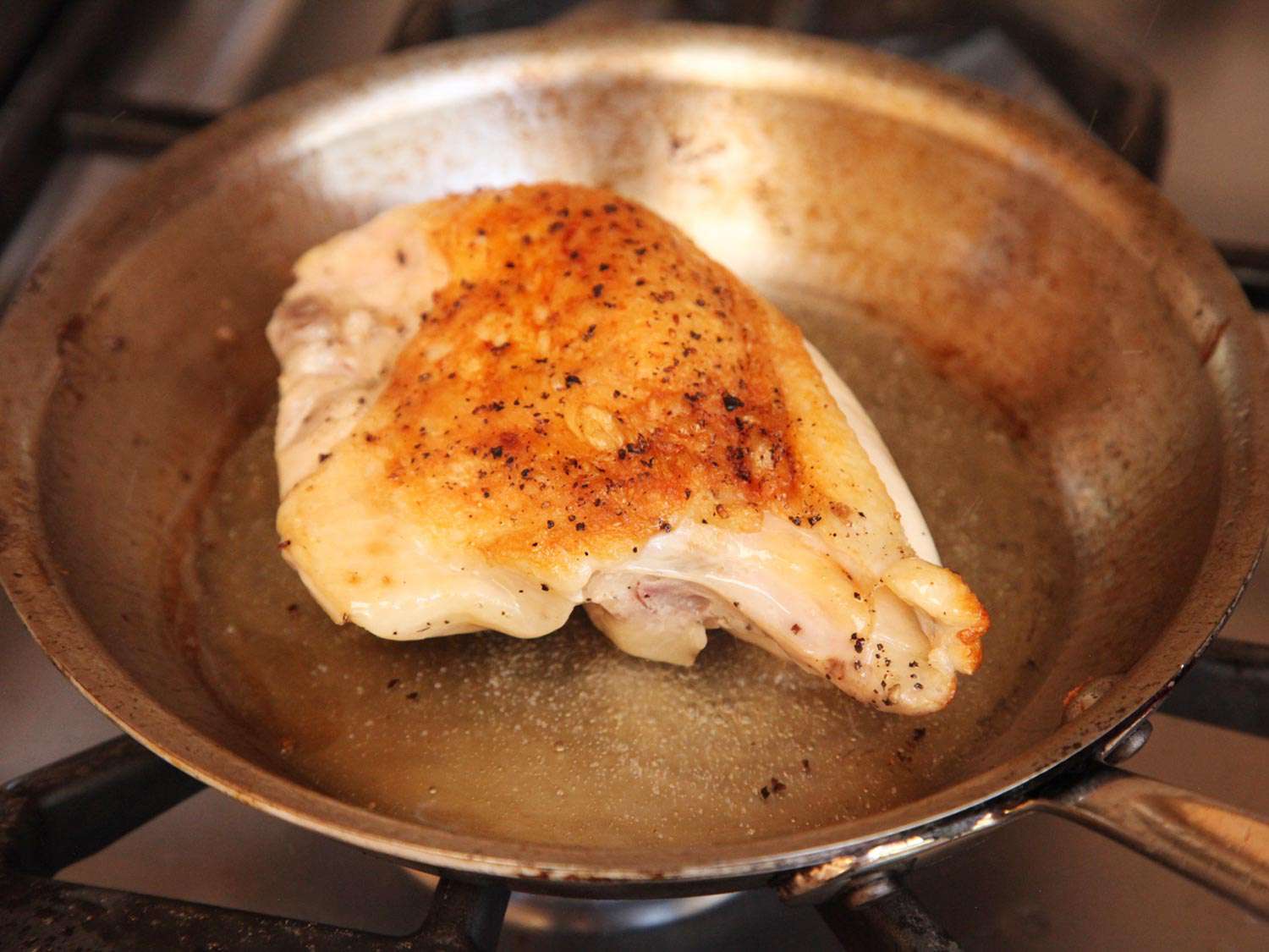 Browned chicken breast in a pan.