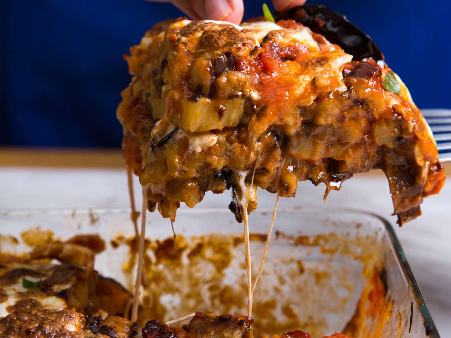 Lifting a large piece of Italian-Style Eggplant Parm from the baking dish.