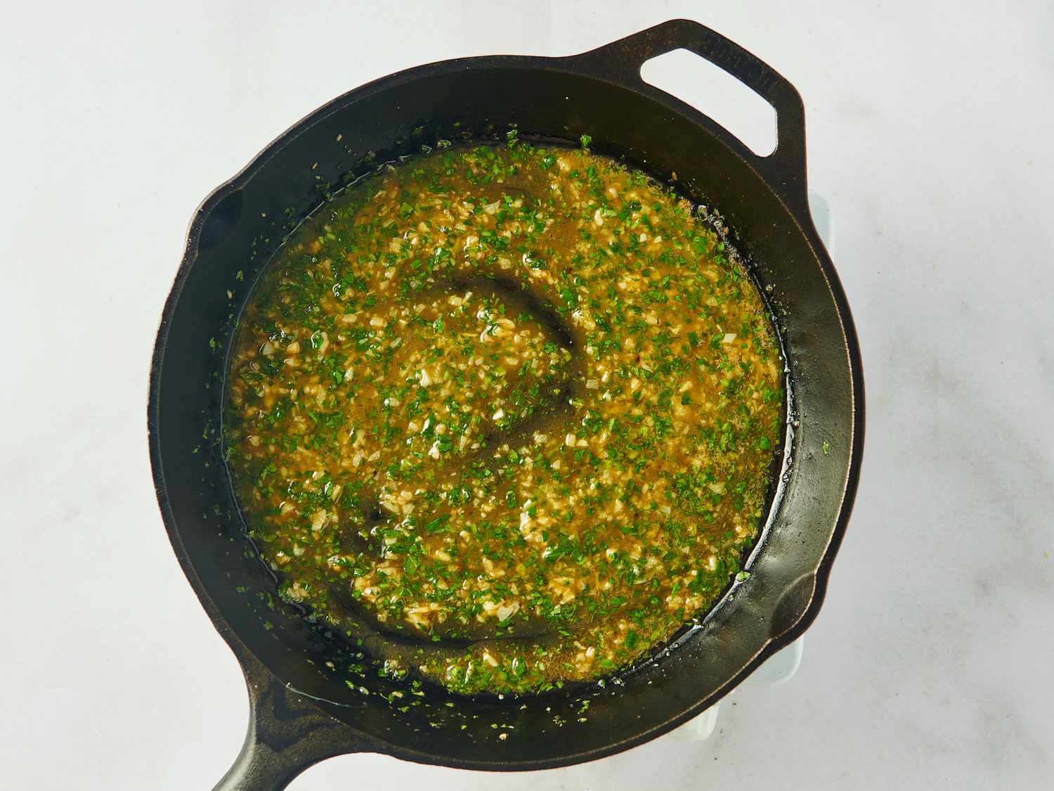 Skillet with sauce containing herbs