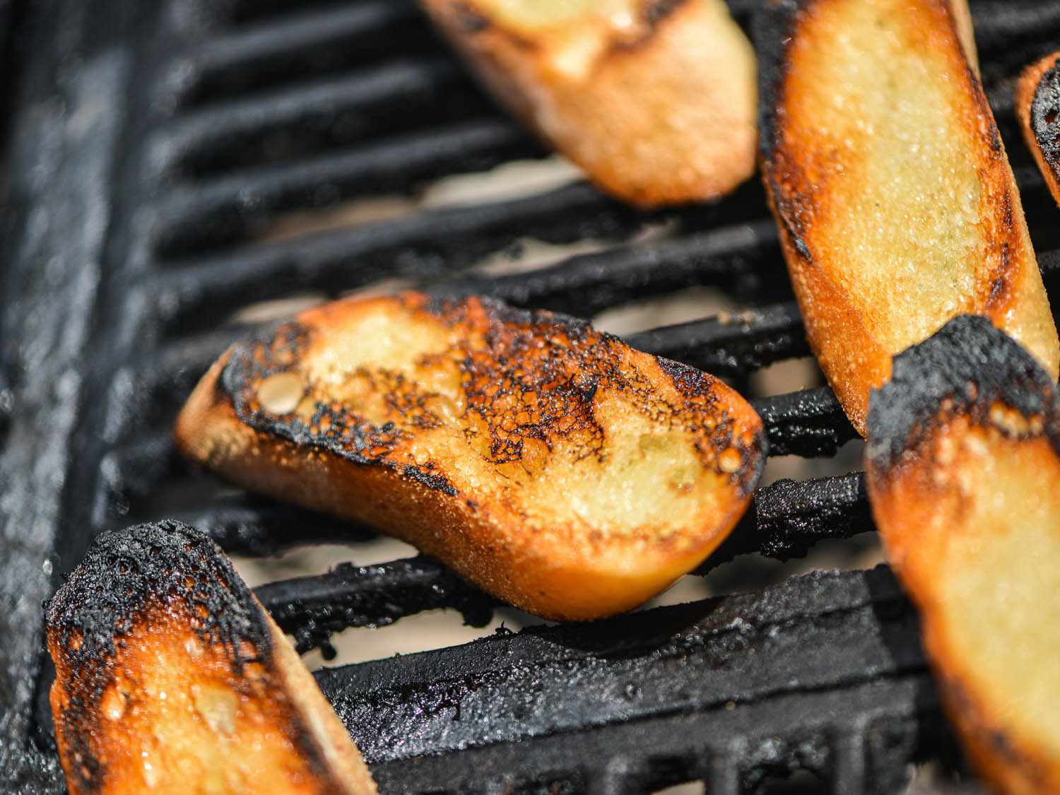 Baguette slices being charred on the grill.
