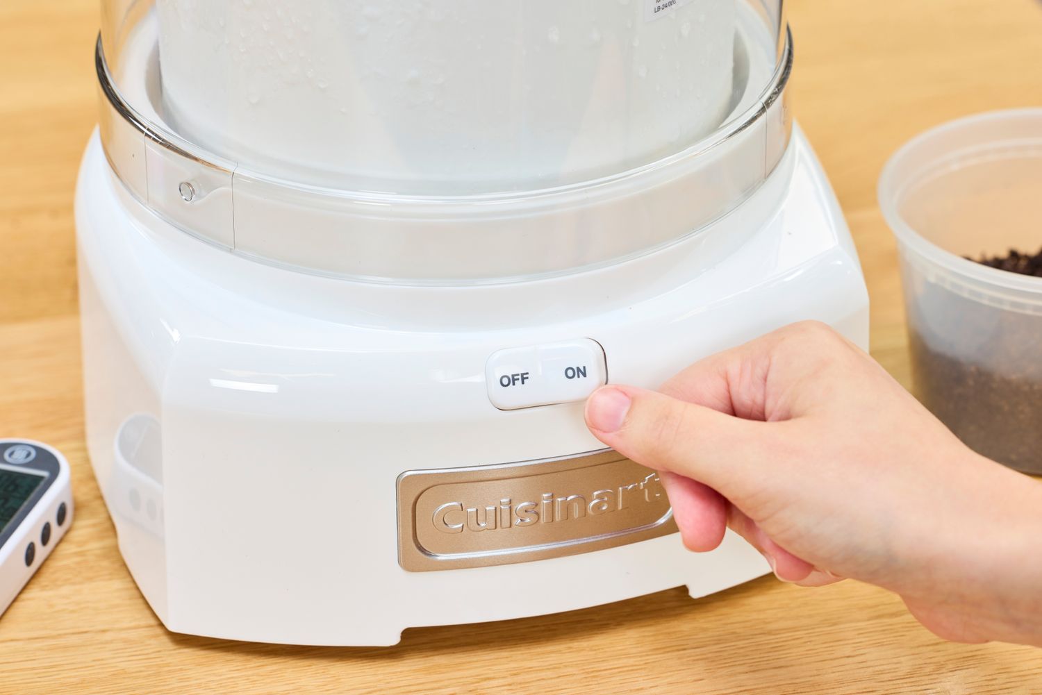A thumb touching a switch on the Cuisinart 1.5-Quart Ice Cream Maker