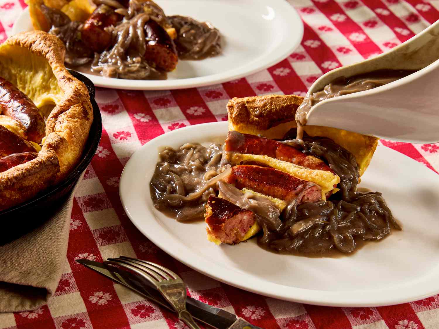 A plate of toad in the hole with onion gravy being poured over