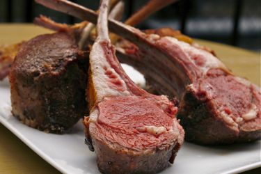 perfect slow-cooked lamb racks arranged standing up on platter