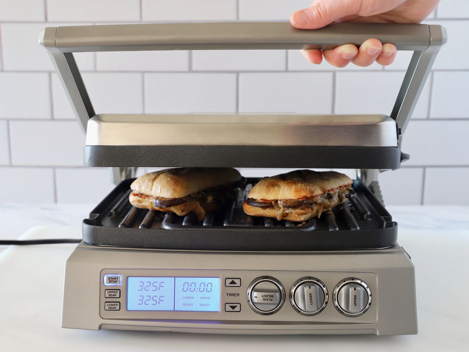 A person lifting the lid of the Cuisinart Griddler Elite.