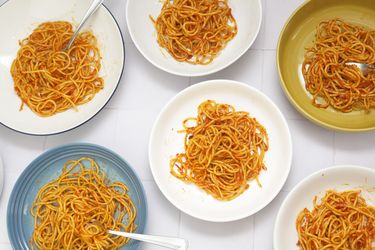 six pasta bowls filled with sauced spaghetti